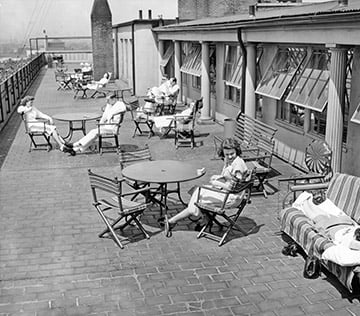 black and white photo of men and women sitting on a rooftop patio